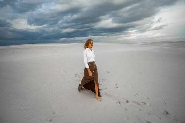 Young woman goes barefoot  in desert on sky background. — Stock Photo, Image