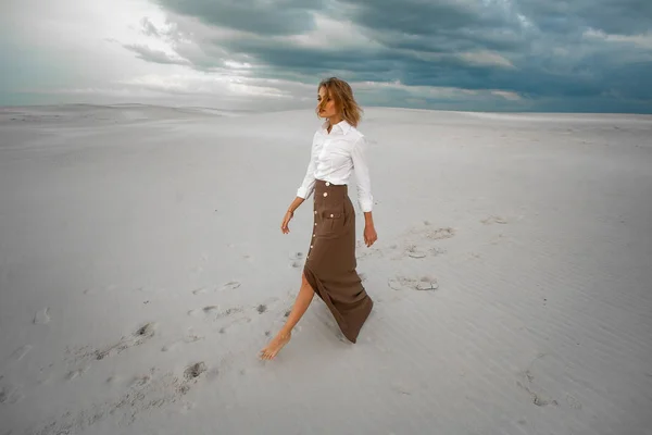 Jonge vrouw gaat barefoot in woestijn op hemelachtergrond. — Stockfoto