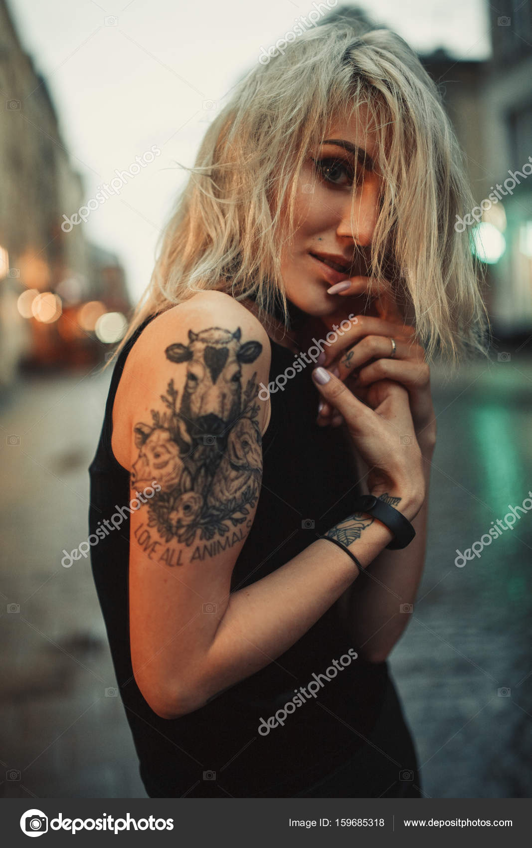 Young woman portrait with tattoo on shoulder standing on city street in evening. Stock Photo by ©stasia04 159685318