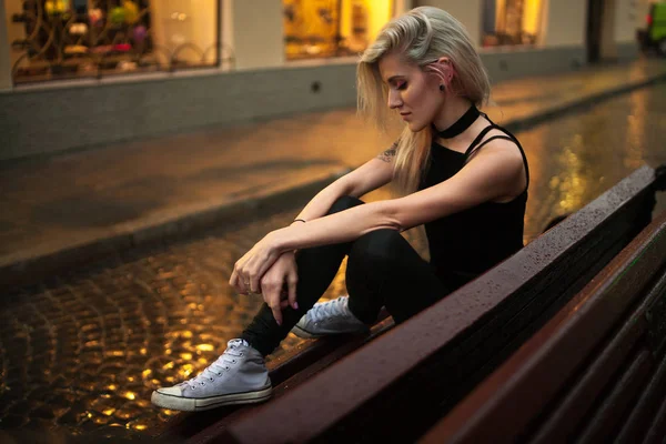 젊은 여자 비에 저녁에 거리 도시에 젖은 벤치에 앉아. — 스톡 사진