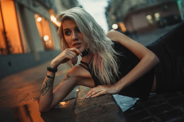 Portret van de jonge vrouw liggend op natte stoep op straat in stad — Stockfoto