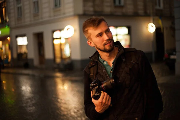 Joven fotógrafo masculino se para en la calle de la ciudad por la noche . — Foto de Stock