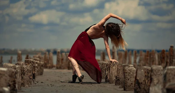 Ballerina in lange jurk is dansen op strand en hemel achtergrond. — Stockfoto