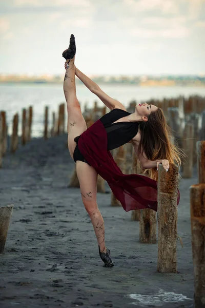 Uzun elbiseli balerin plaj arka plan üzerinde dans ediyor.