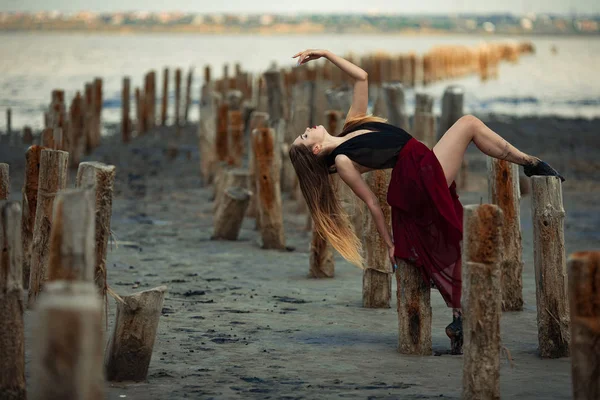 Ballerina in abito lungo sta ballando su sfondo spiaggia . — Foto Stock