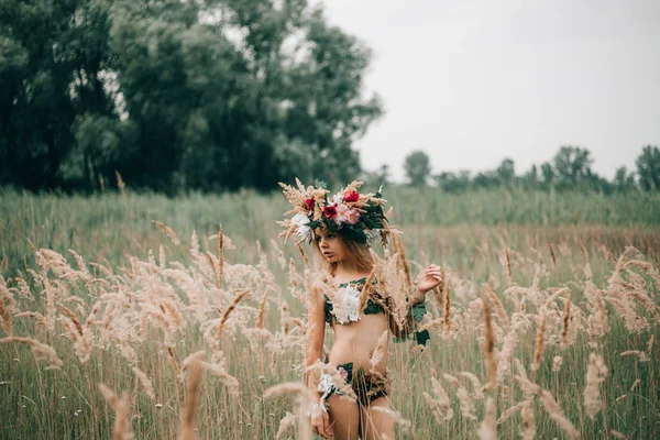 Hermosa niña en la imagen de la ninfa se encuentra entre los pastos en el prado . —  Fotos de Stock