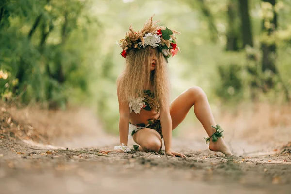 Beautiful little girl in image of nymph dryad sits in forest road. — Stock Photo, Image