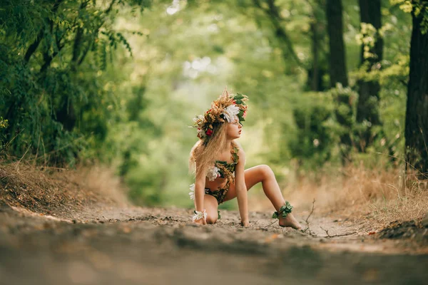 Krásná holčička v obrázku nymfy dryáda sedí v lesní cesta. — Stock fotografie