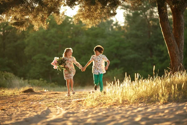 Liten flicka och pojke som körs i skogen road och hålla händerna — Stockfoto