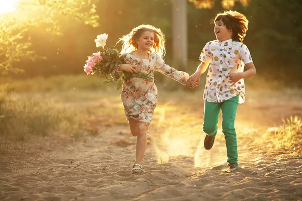 Niña y niño están corriendo en el camino del bosque y tomados de la mano — Foto de Stock