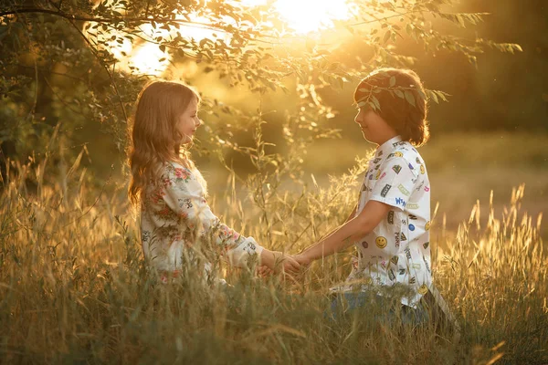 Mädchen und Junge sitzen im Gras und halten sich an den Händen. — Stockfoto