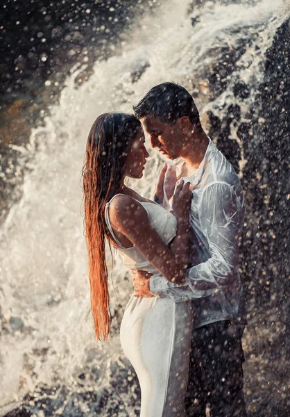 Jeune couple amoureux câlins sous la pulvérisation de cascade . — Photo