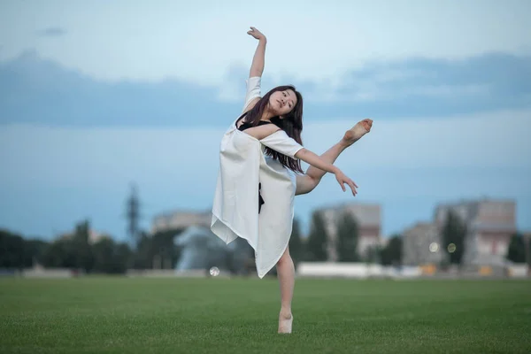 Bailarina fica em pose de engolir no gramado . — Fotografia de Stock