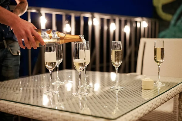 La mano del hombre derrama champán en las gafas de vino . — Foto de Stock