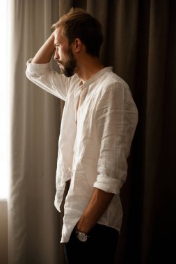 Genç adam beyaz gömlekli penceresinde arama yapar.