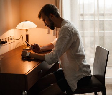 Genç adam masada oturur ve onun smartphone vasıl görünüyor.