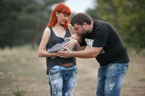 Glückliche junge Familie mit Neugeborenem auf Spaziergang im Park. — Stockfoto