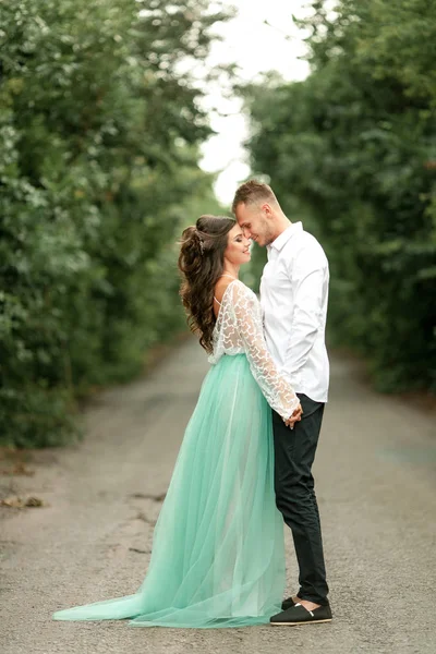 Bruden och brudgummen står på skogsväg och Håll händerna. — Stockfoto