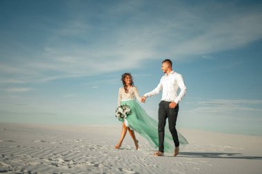 Gelin ve damat el ele, neşeyle gülmek ve çıplak ayakla yürümek