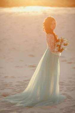 Gelin buketi ile çölde kum üzerinde duruyor. Arka ışık ve Yapıştır