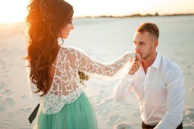 Günbatımı ve kı üzerinde önce çölde bir diz gelin damat duruyor