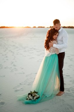 Gelin ve damat çölde günbatımı, gülümseme ve kucaklama standı. 