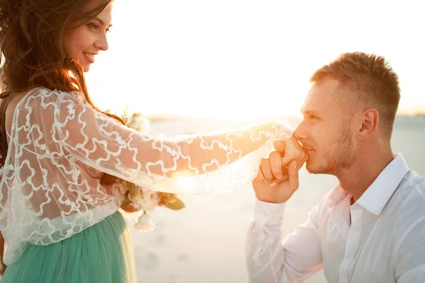 Bräutigam steht vor Braut in Wüste und küsst ihre Hand. Seite vi — Stockfoto