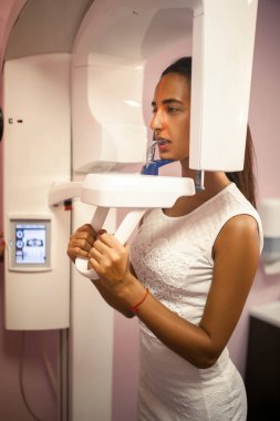 Genç kadının diş röntgen cihazı üzerinde x-ray yapması.