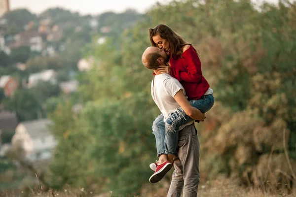 Giovane uomo sollevato ragazza e si baciano a piedi nella foresta . — Foto Stock