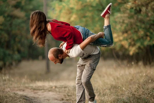 Joven hombre levantó a chica en su espalda y la lleva . —  Fotos de Stock