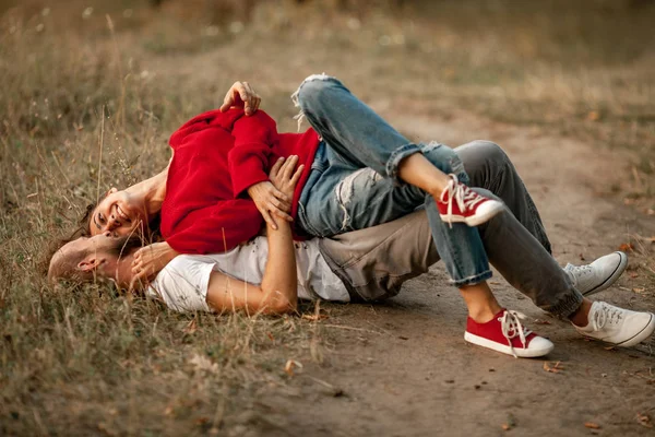 Enamorado casal mentiras, sorrisos e abraços no caminho da floresta . — Fotografia de Stock