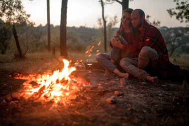 Aşık çift piknik şenlik ateşi alev arka plan üzerinde oturur.