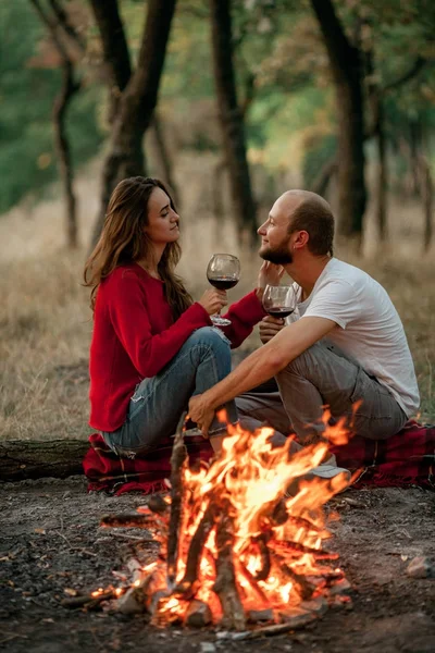 Couple amoureux assis sur pique-nique dans la forêt sur fond de flamme de feu de joie . — Photo