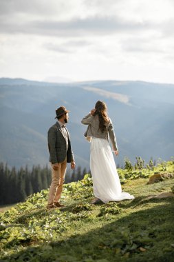 Yeni evliler ve stand dağlar mesafe içine bakmak.