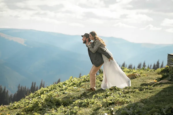 Yeni evliler standı, sarılmak ve dağlarda iyi eğlenceler. — Stok fotoğraf