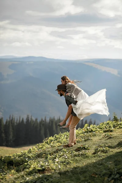 Yeni evliler standı, sarılmak ve dağlarda iyi eğlenceler. Damat br taşır — Stok fotoğraf