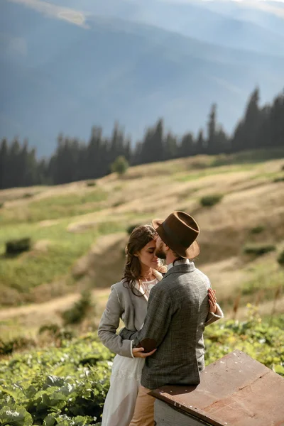 Yeni evliler ve stand dağlar özgeçmişlerine sarılmak. — Stok fotoğraf