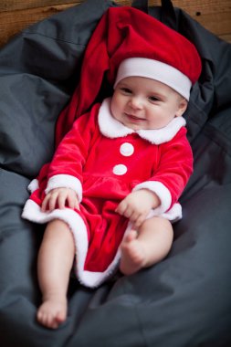 Noel Baba kostüm kız bebek yastık ve gülümsüyor arasında oturur.