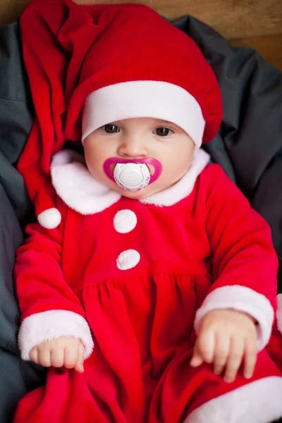 Niña en traje de Santa Claus se sienta entre la almohada . —  Fotos de Stock