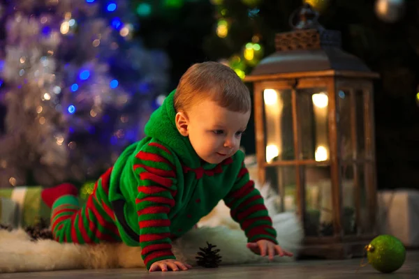 Niño se arrastra a la bola de Navidad en el suelo cerca del árbol de Navidad . —  Fotos de Stock