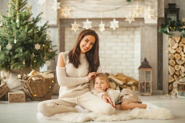 Anne oturur, gülümsüyor ve kızı Noel süslemeleri arka planı sonraki yatıyor.