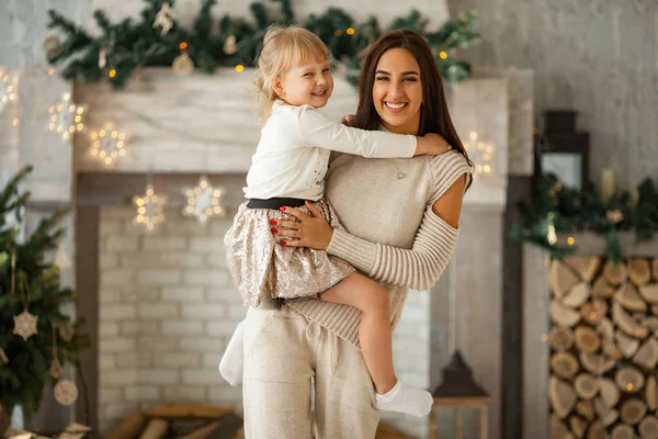 母は彼女の腕の中で小さな娘を保持しているし、彼らはクリスマスの装飾の背景と笑顔. — ストック写真