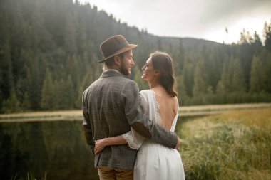 Gelin ve damat stand, kucaklama ve her diğer Orman Gölü yakınındaki bir görünüm.