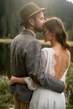 Gelin ve damat stand ve orman göl kenarında kucaklamak. Arkadan Görünüm. Portre.