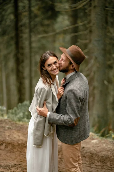 Bruden och brudgummen stå på skogsväg, omfamning och laught. — Stockfoto