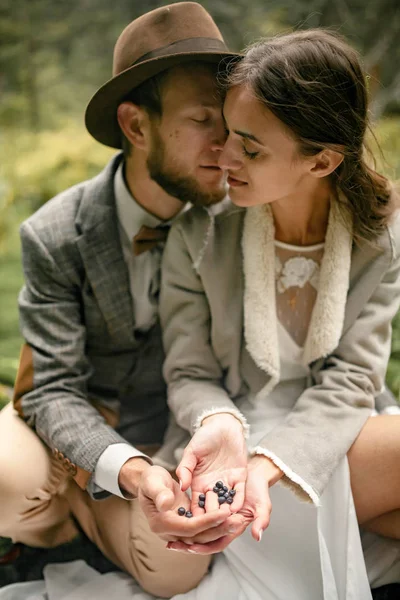 Gelin ve damat ormanda otur ve yaban mersini ellerini tutun.