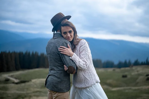 Novia y novio de pie y abrazo en el fondo de las montañas de los Cárpatos . — Foto de Stock