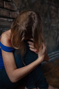 Üzgün kadın aile içi şiddet ve istismar kurbanı vücudunda yaralar ve yaralar ile katta oturur. Portre.