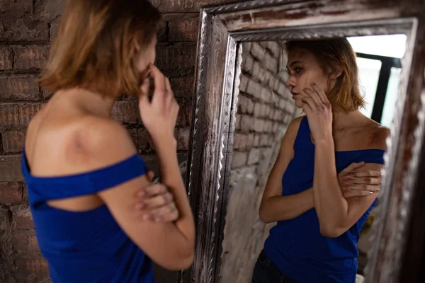 Жінка-жертва домашнього насильства і жорстокого поводження стоїть біля дзеркала і дивиться синці на її обличчя . — стокове фото