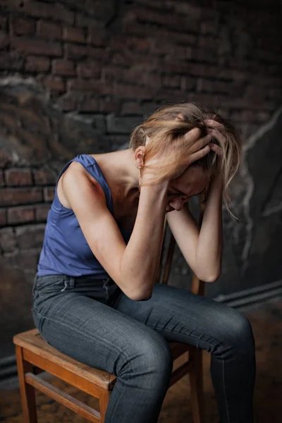Plačící žena obětí domácího násilí a zneužívání sedí na židli s modřiny a rány na její tělo. — Stock fotografie